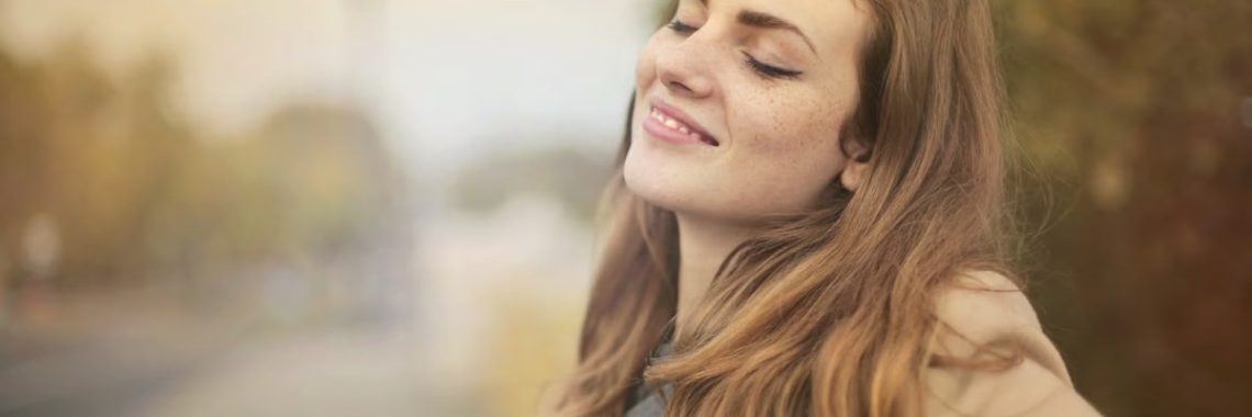 Portrait of a woman with closed eyes, enjoying the outdoors in autumn. Bright and serene.